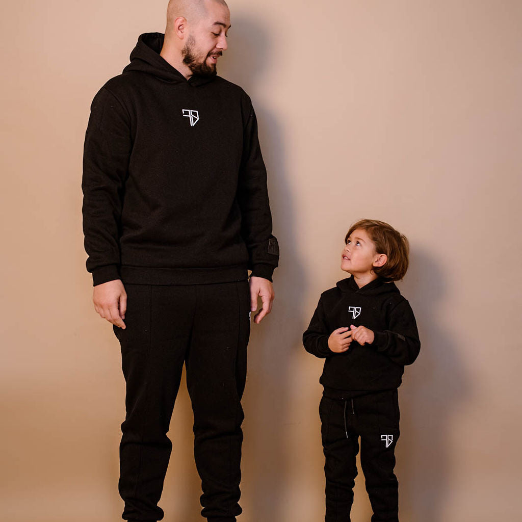 vader en zoon in zwart trainingspak met capuchon