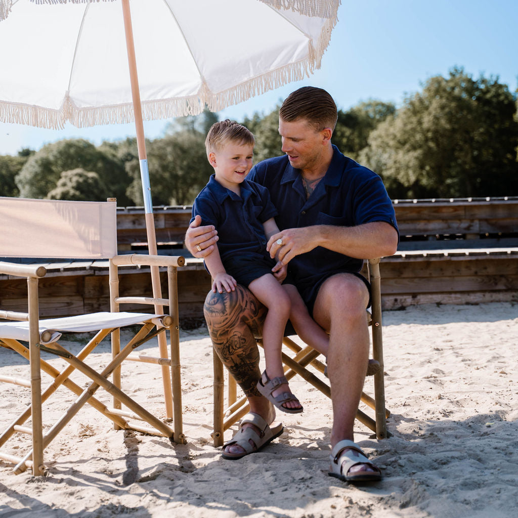 Man en kind in identieke navy blauwe terry overhemden op vakantie