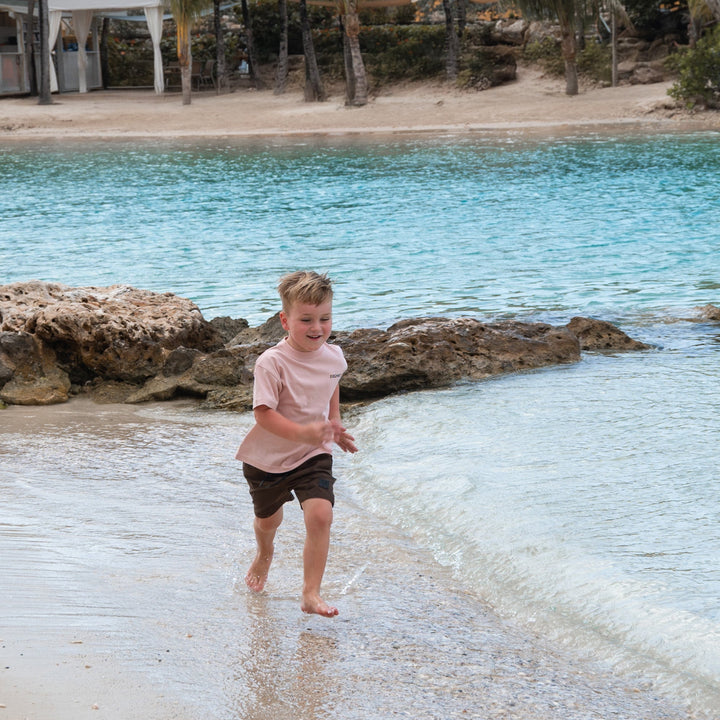 kind draagt zacht roze kids T-shirt van 100% katoen met nieuw Frenky S logo op de voorkant en bekend logo op de achterkant