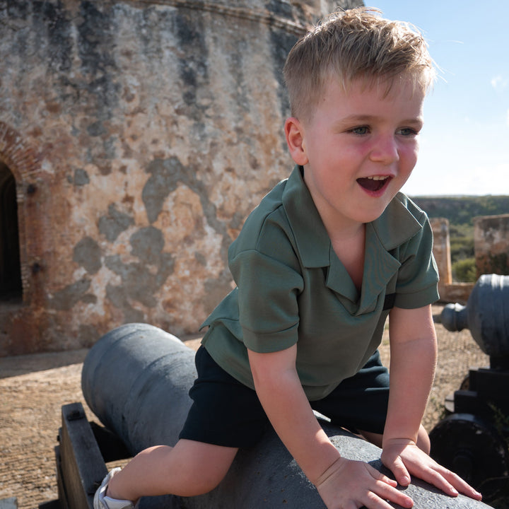 kind draagt groene reverse collar scuba polo van Frenky S met logo patch op de borst