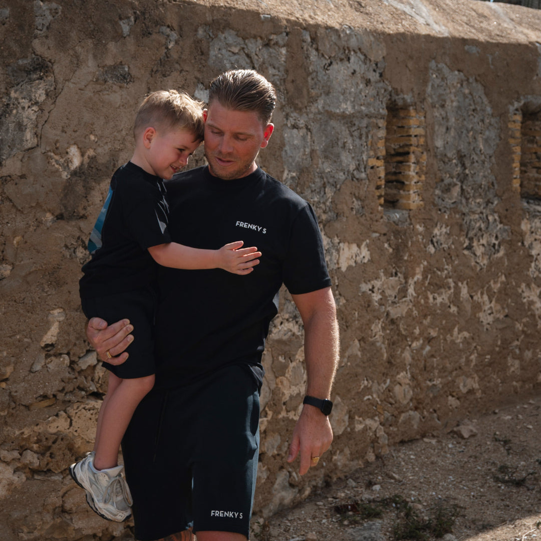 kind draagt zwart kids Travel T-shirt van Frenky S met rugprint vliegtuigraampje met uitzicht op Koh Samui