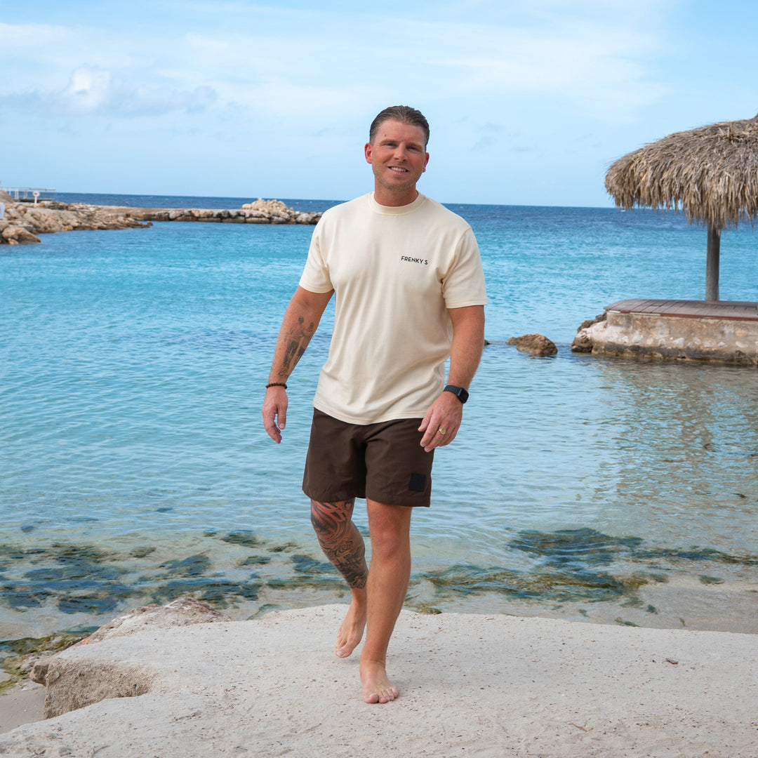 man draagt bruine heren zwembroek van Frenky S met ritszakken op het strand